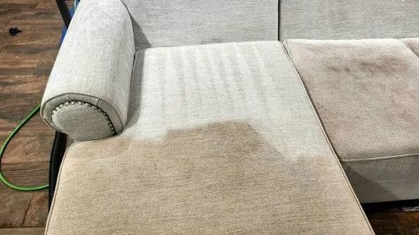 Upholstered sofa during cleaning with a visible cleaned section